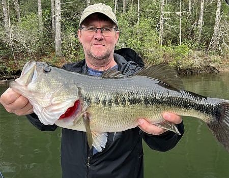 Man holds up fish caught on trip