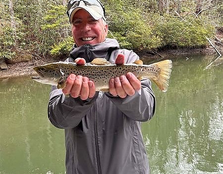 Man holds up fish caught on trip