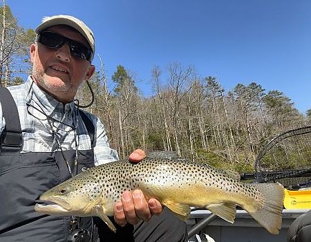 Man holds up fish caught on trip