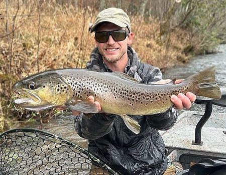 Man poses with fish caught on river