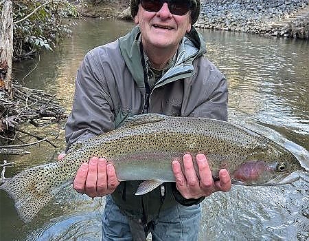 Older gentleman holds up fish in two hands