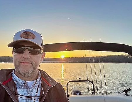 Man on boat at sunrise on fly-fishing Blue Ridge trip