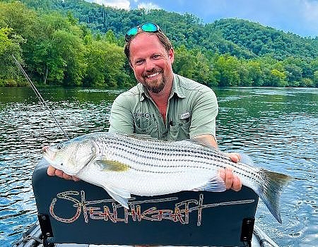 Man poses with fish caught on fly fishing trip